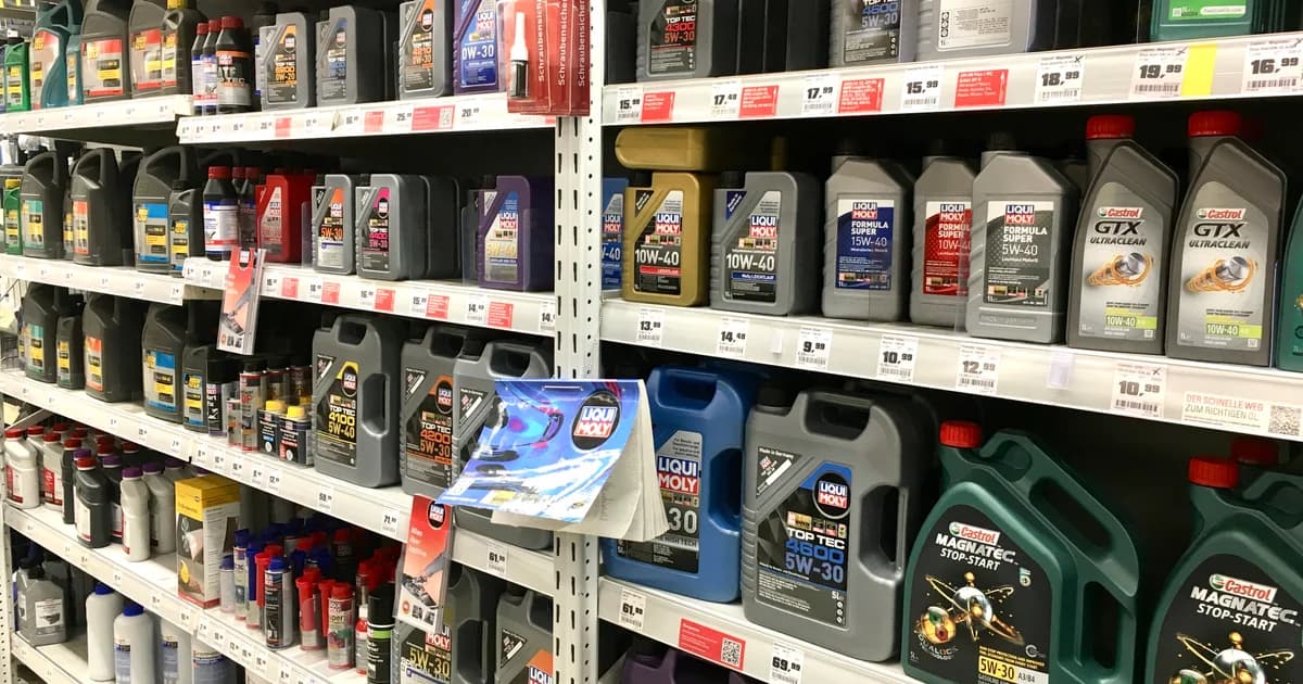 Rayonnage de plusieurs bidons d'huile moteur de différentes marques et viscosités dans un magasin de pièces automobiles